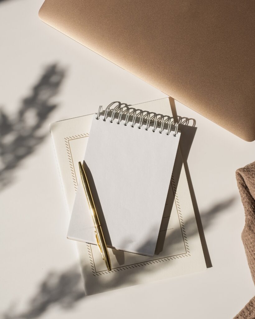Coastal-inspired journal flat lay with notebook, pen, and soft natural light representing self-discovery journaling and reflection.
